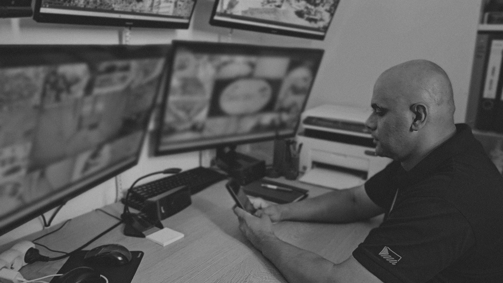 Michal Gábor at the operations desk, reviewing site feeds and his phone.
