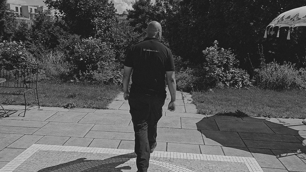 A Sentinel Security team leader on patrol across the grounds of a residential assignment, in black and white.