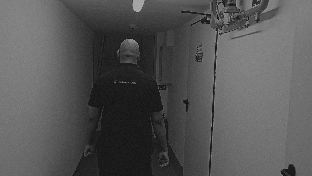 A Sentinel Security officer on rounds in a building service corridor with fire-safety equipment.
